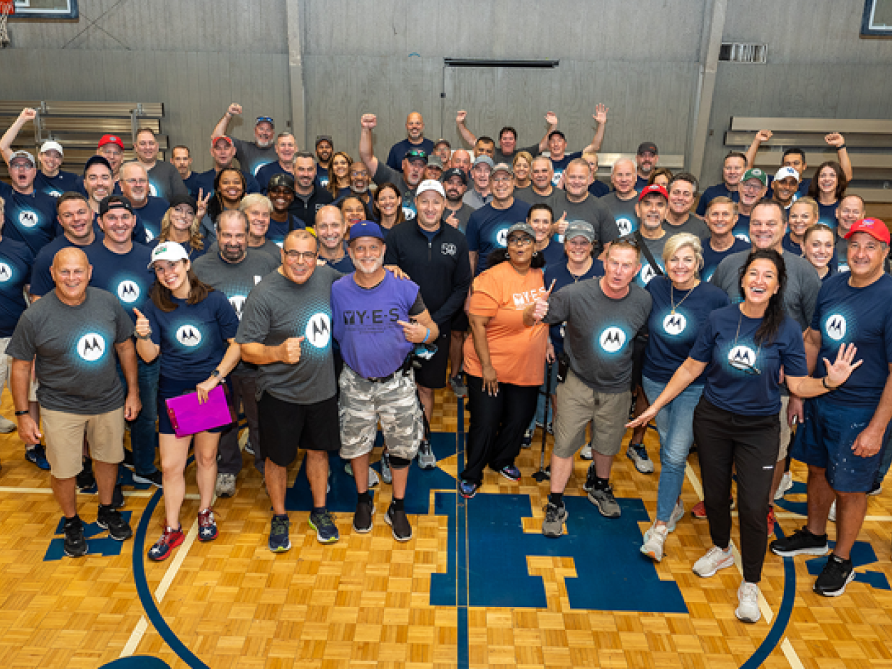 Group of volunteers wearing Motorola shirts standing in gym