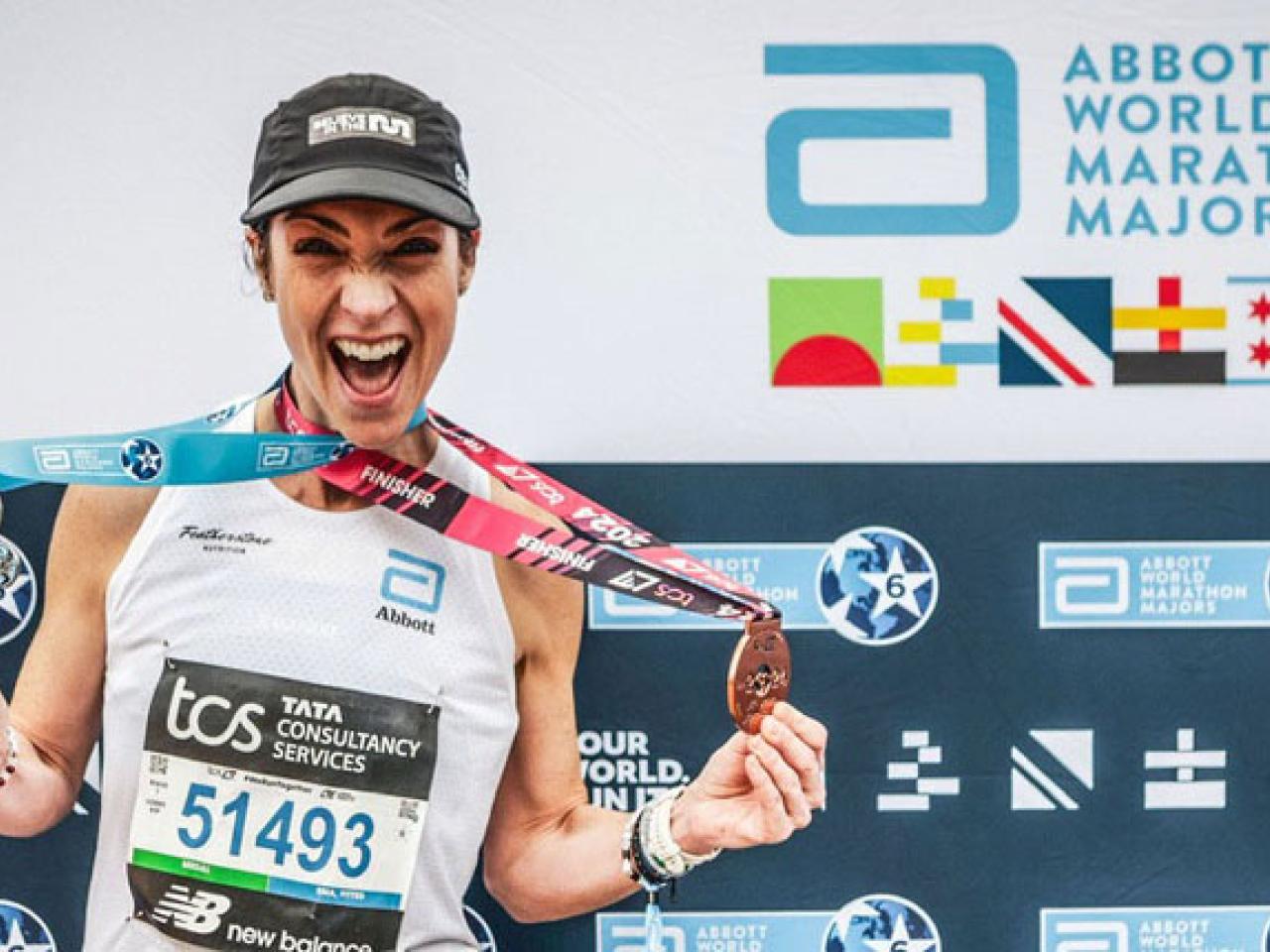 A person wearing medals in front of an Abbott World Marathon Majors back drop 