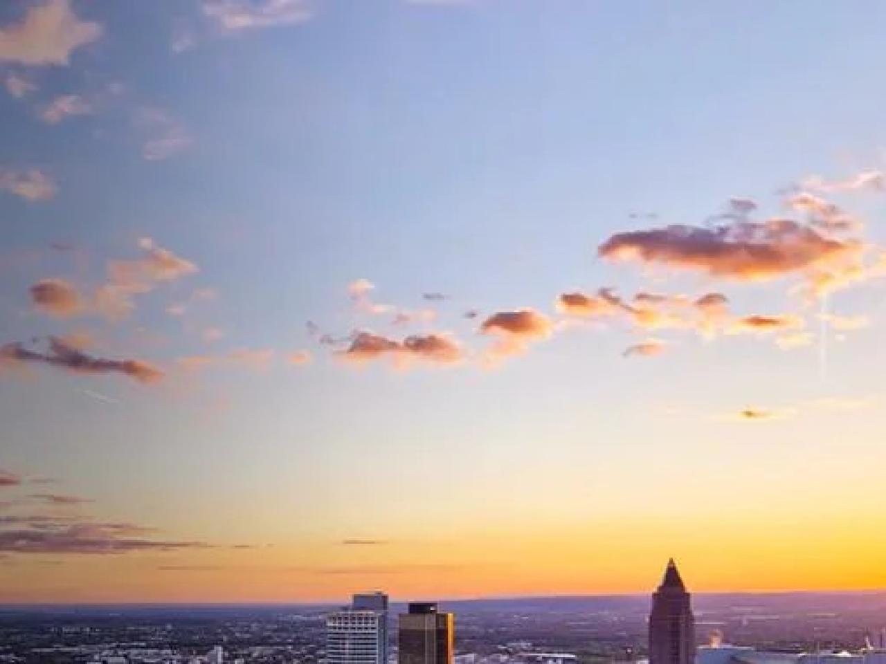 A setting sun in an open sky over a city landscape