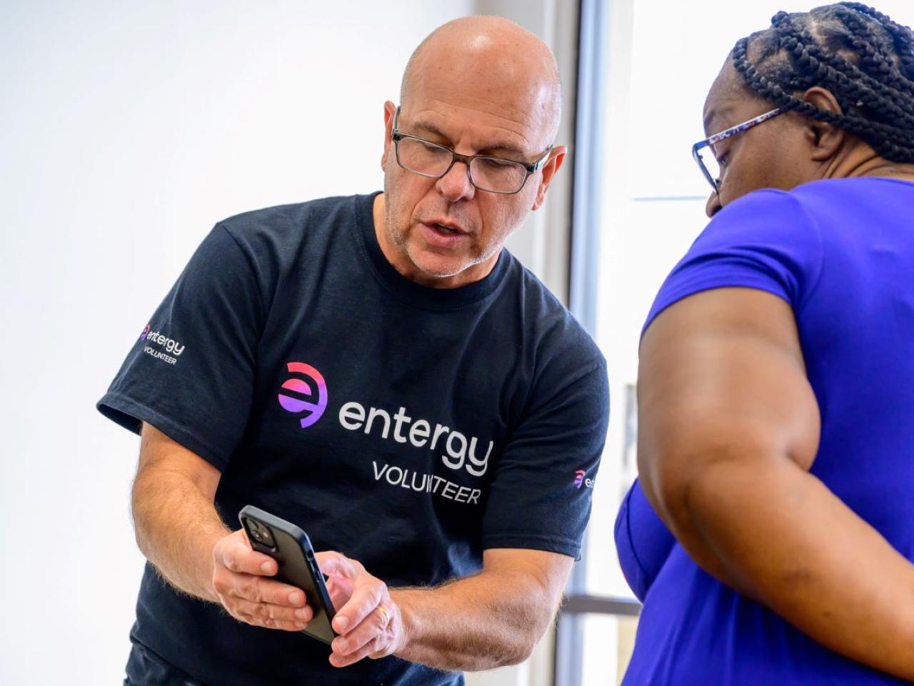 A volunteer and another person looking at a cell phone.