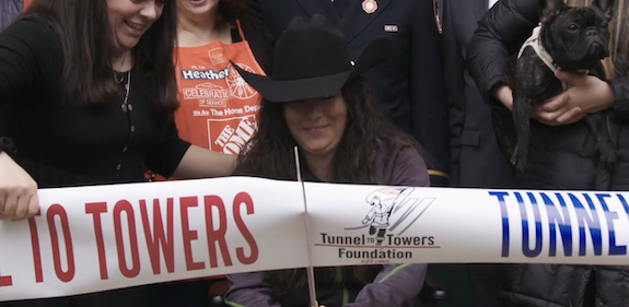 U.S. Army Specialist (SPC) Maggie Bilyeu shown cutting the ribbon in front of her new home.