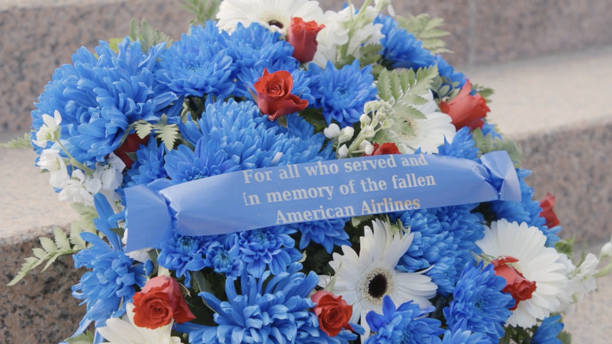 A flower bouquet with ribbon that reads "For all who served and In memory of the fallen American Airlines"
