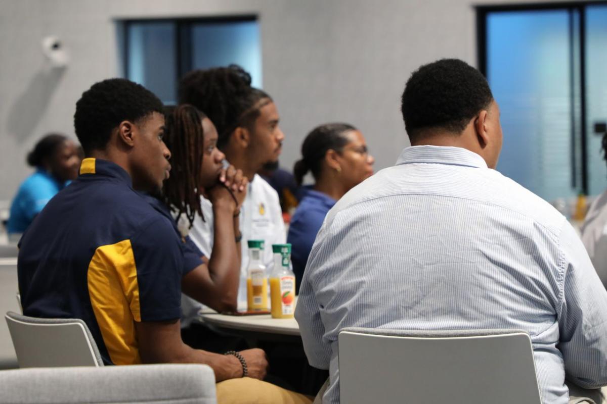 Students sat at a table looking towards the front of the room