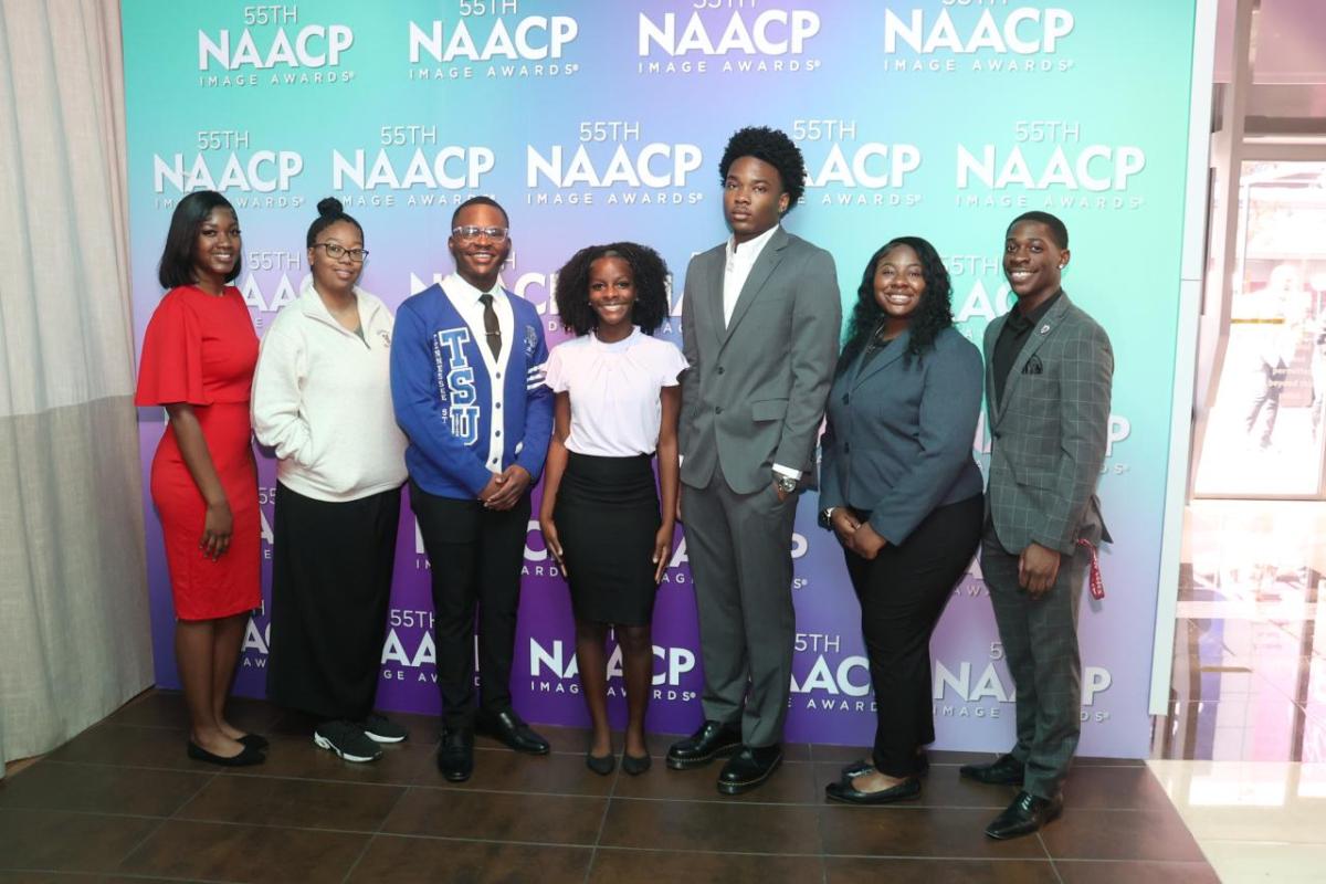 A group of people stood in front of a NAACP Image Awards event backdrop 