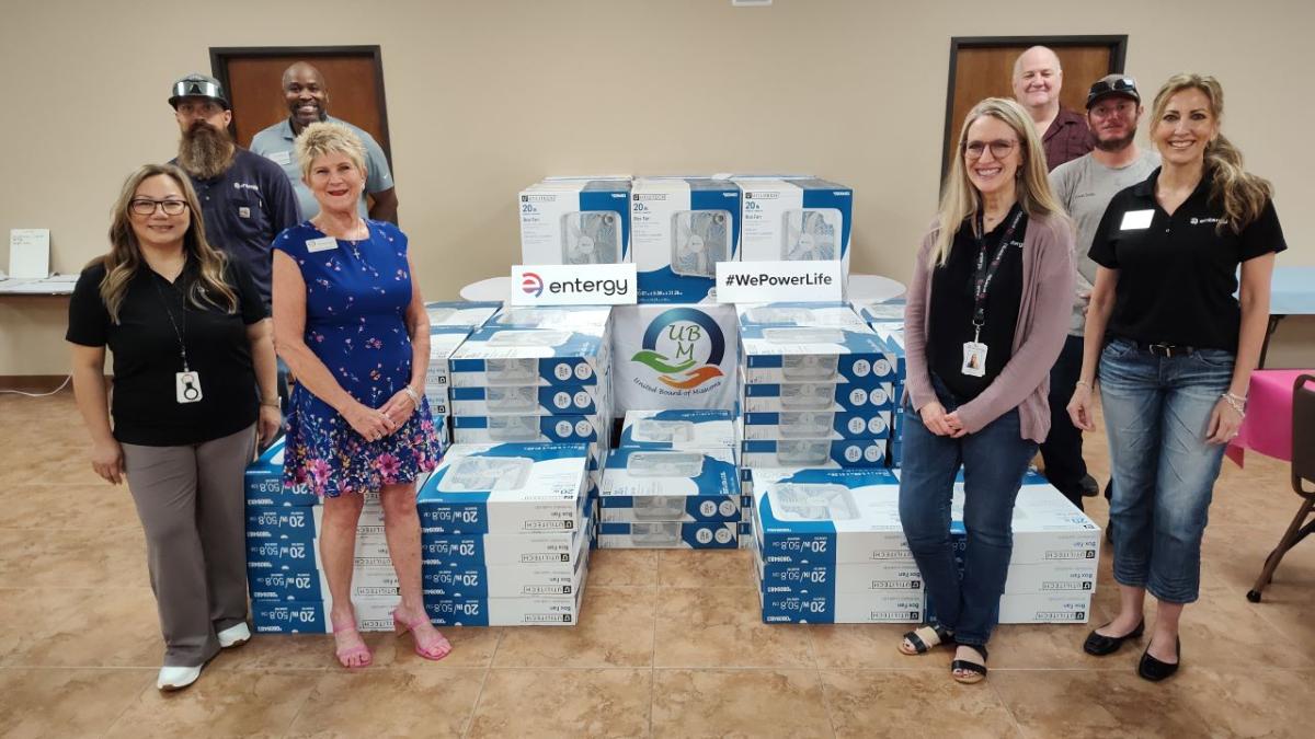 People standing next to stacks of new fans in boxes