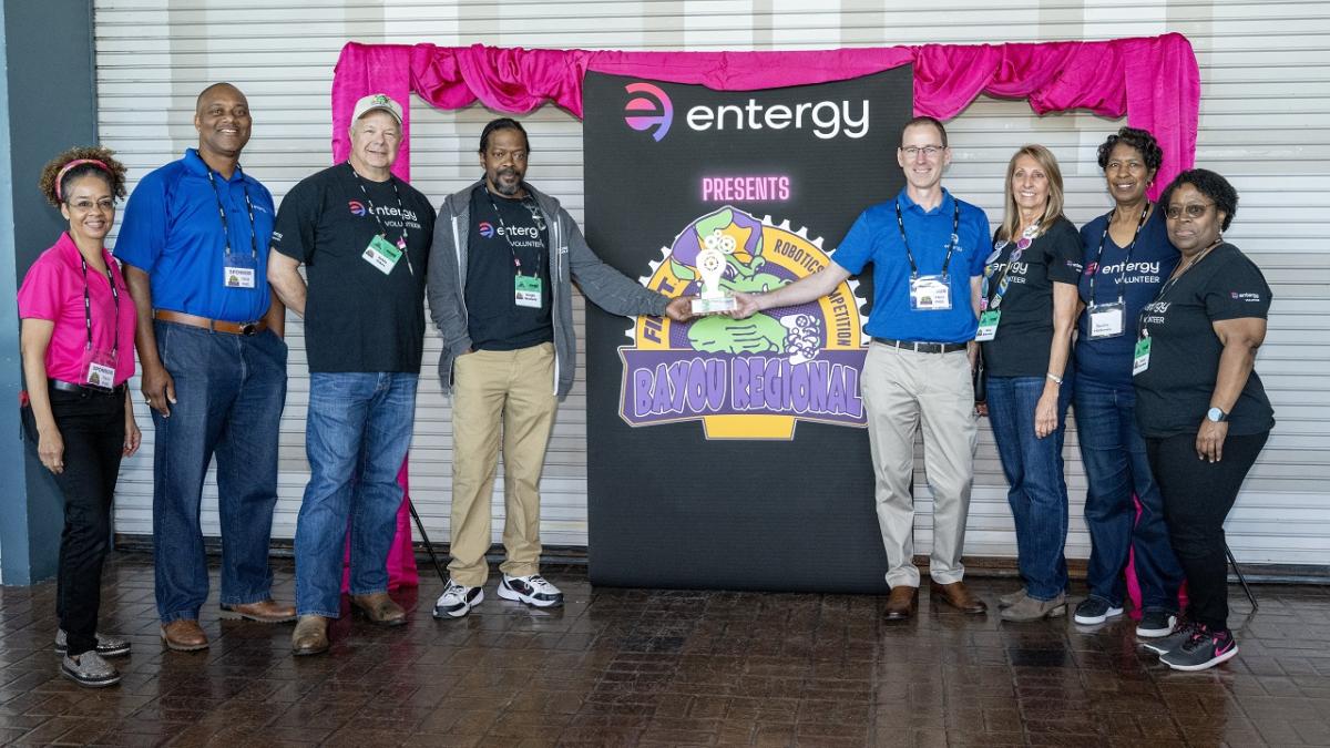 People standing together next to an Entergy sign
