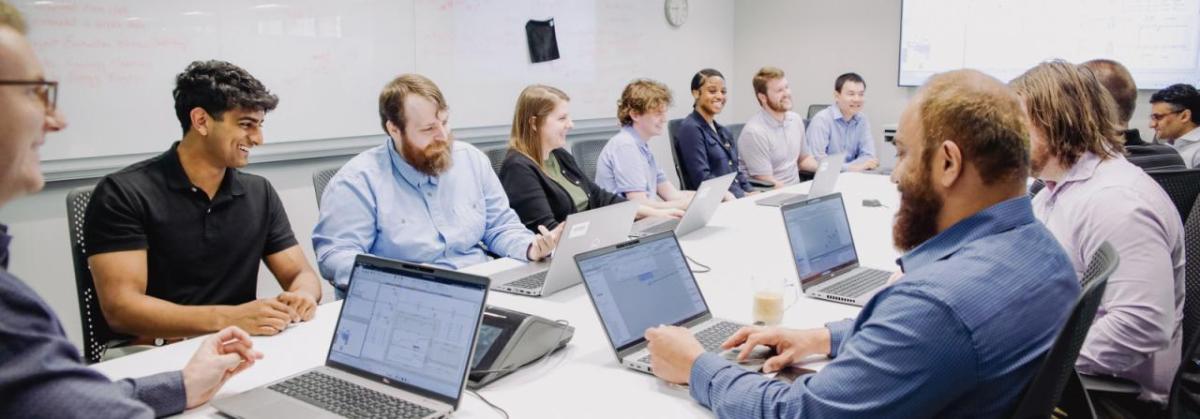 People sitting at a conference table working on laptops