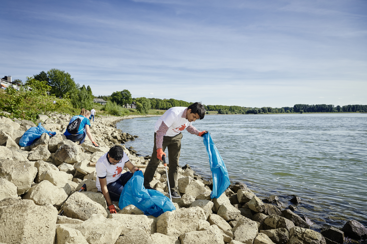 People picking up garbage by a body of water