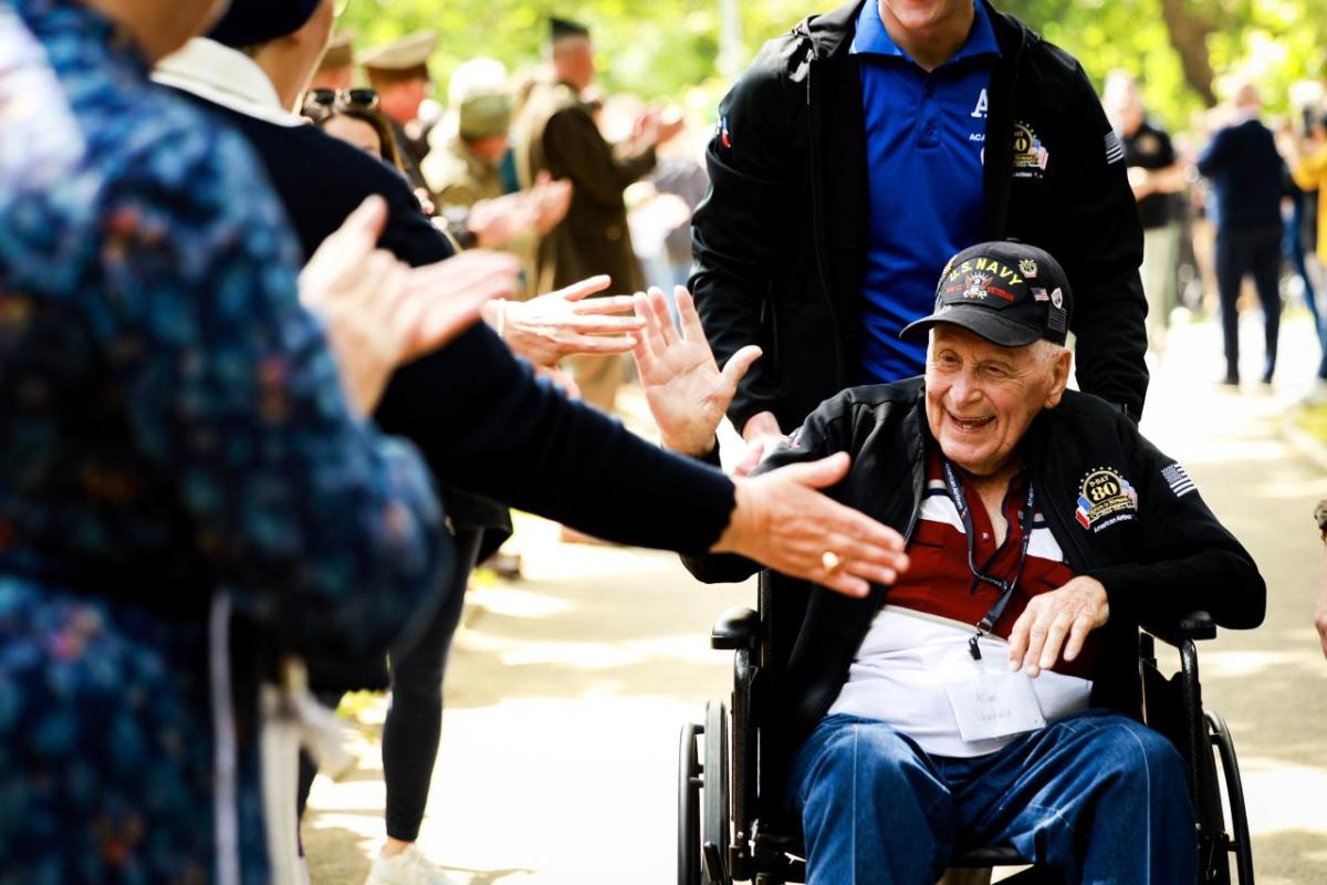 People clapping and reaching out to a war veteran 