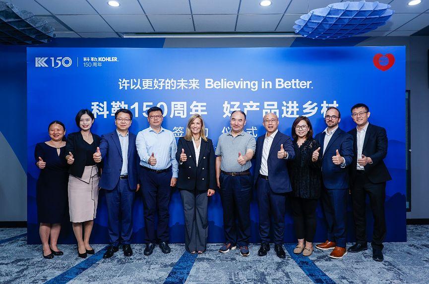 A group of people stood together in front of of a blue "believing in better" backdrop 