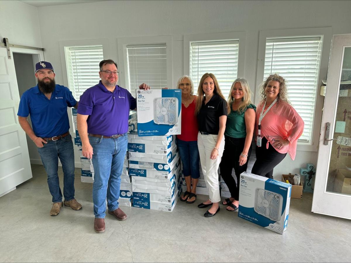 People standing next to stacks of new fans in boxes