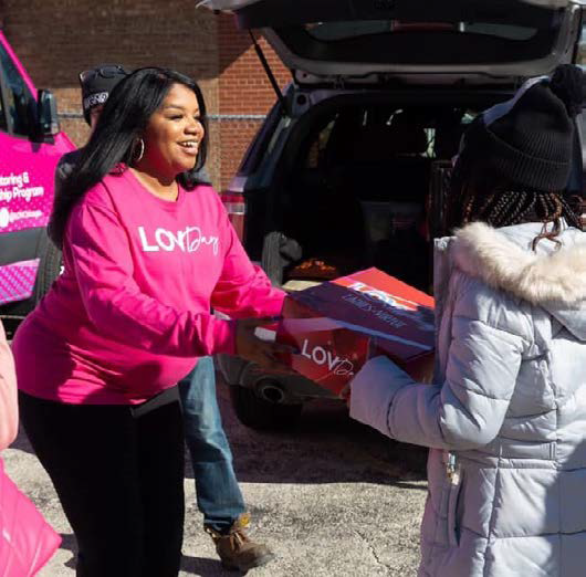 A person in a pink shirt exchanging a box with someone