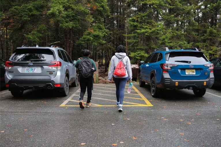 Two people walking between two Subaru cars