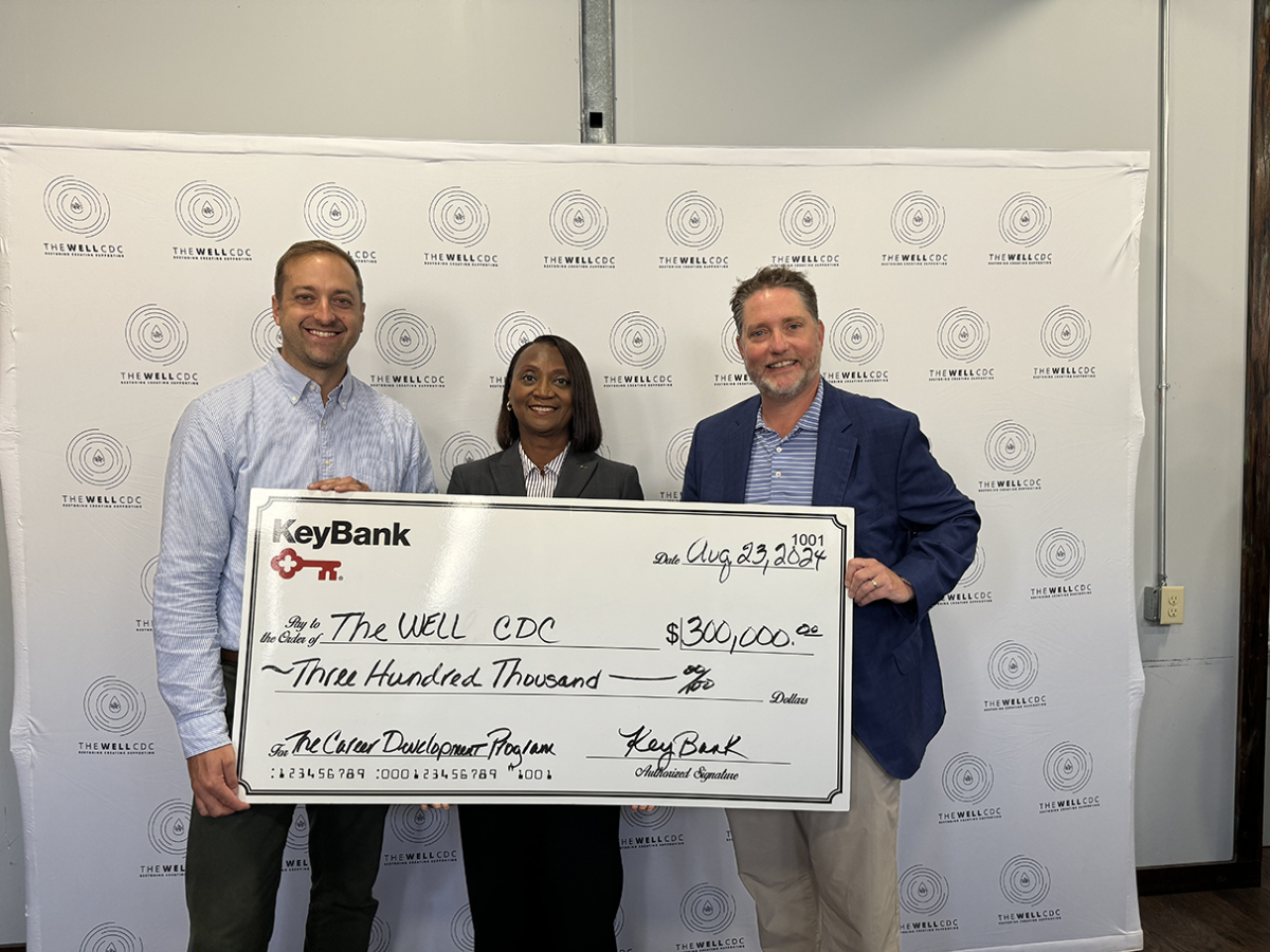 Three people posing with an oversized check