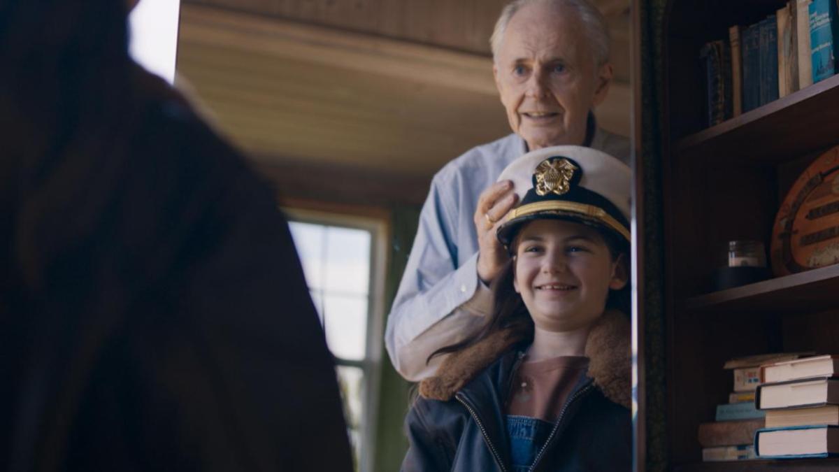 An adult putting a military hat on a child 