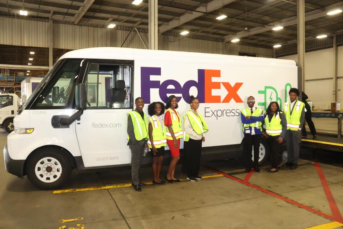 A group of people wearing hi-viz vests while stood next to a FedEx express van