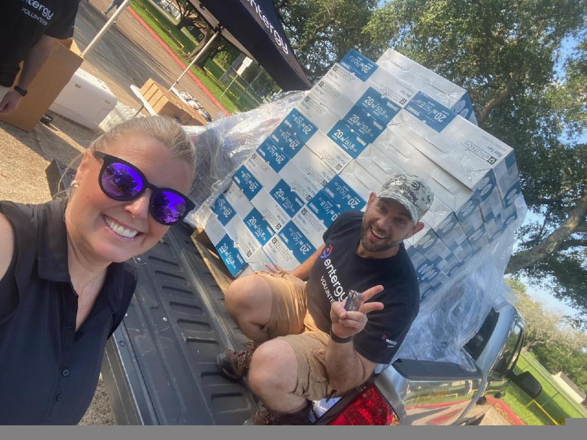 People smiling next to new fans in boxes placed in the bed of a pickup truck