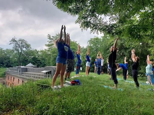 A group outside on grass, reaching their hands up