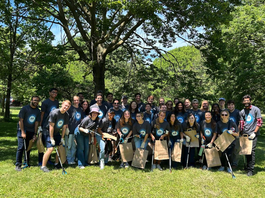 A group of people in Motorola t-shirts posing and smiling together under trees