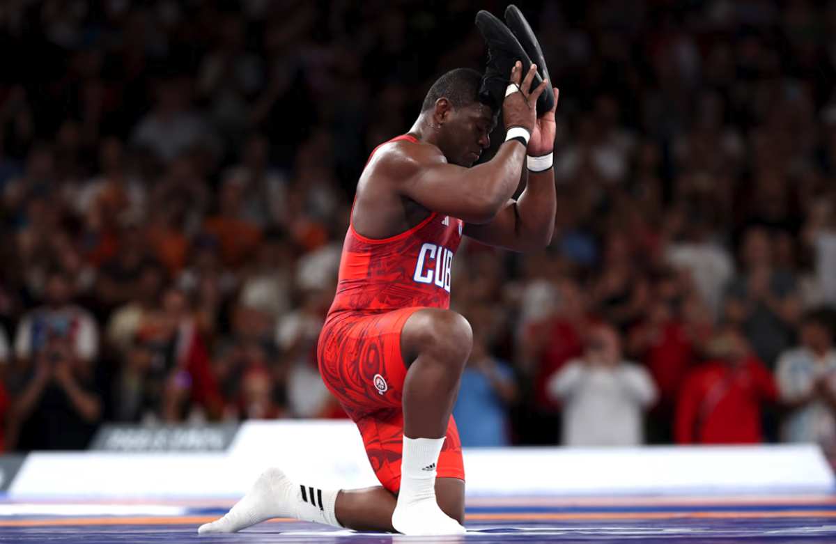 An Olympian on a mat holding shoes above their head