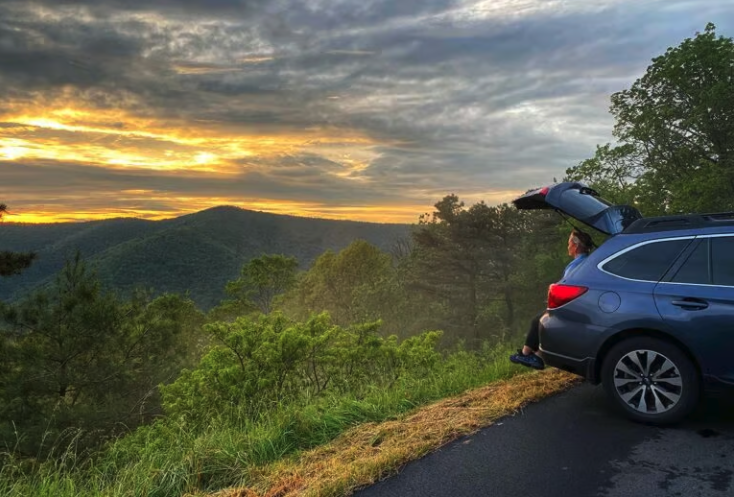 Someone looking out at a sunset from the back of a Subaru car
