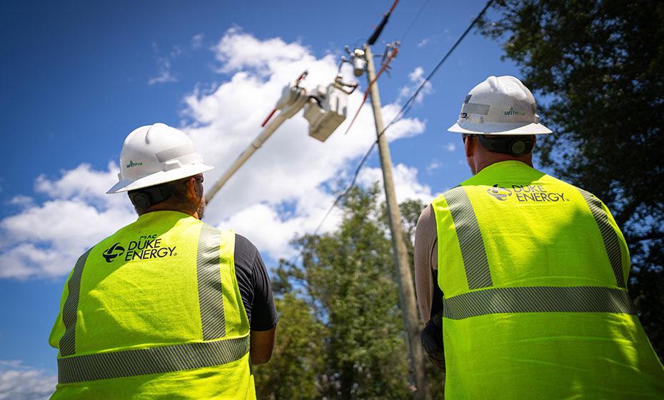 Two workers in hard hats and reflective vests shown from the back