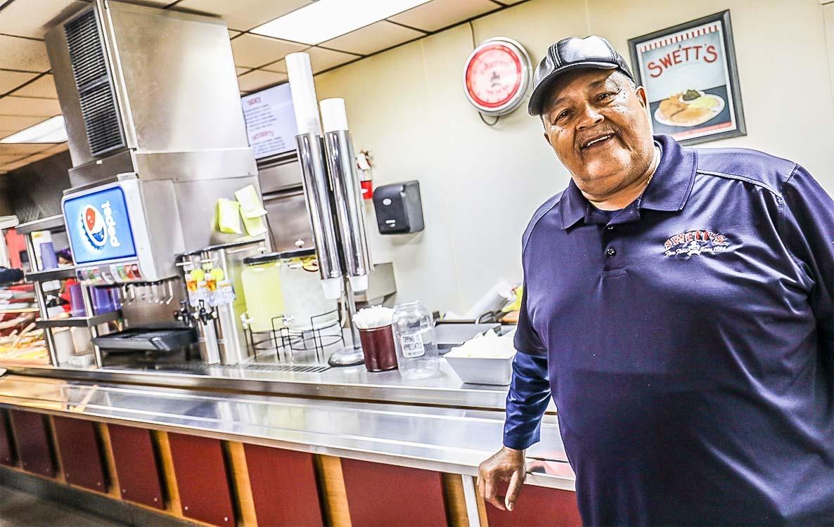 David Swett, cashier, at a counter