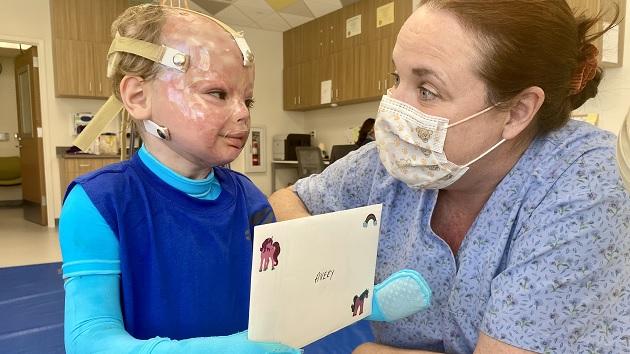 Avery and a medical professional smiling at each other. The child holds a card with "Avery" on it.