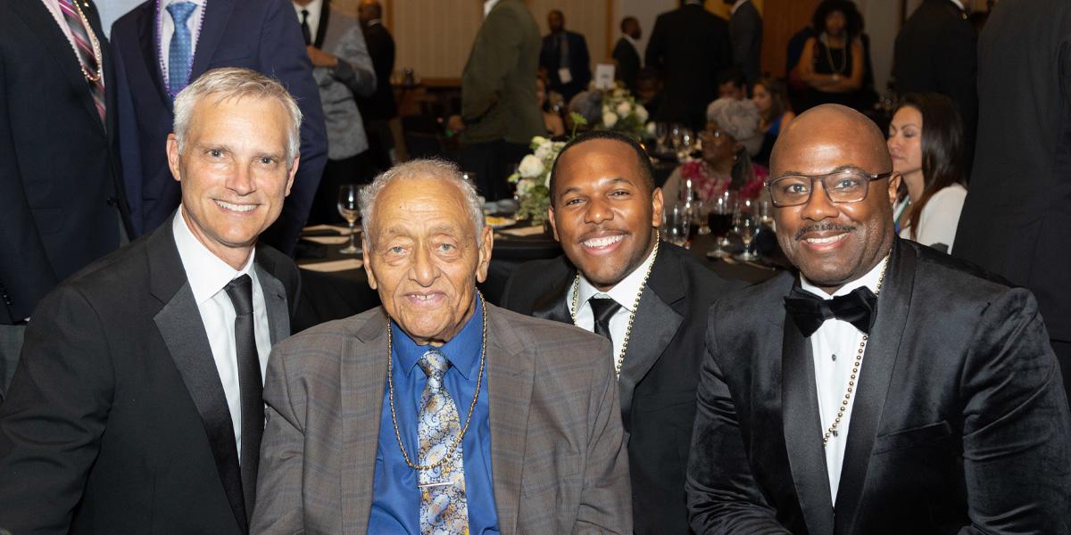 four people in suits and ties at a fancy banquet