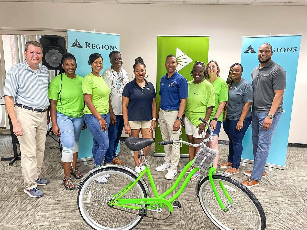 a group of people inside, regions banners behind them. a green bike in front