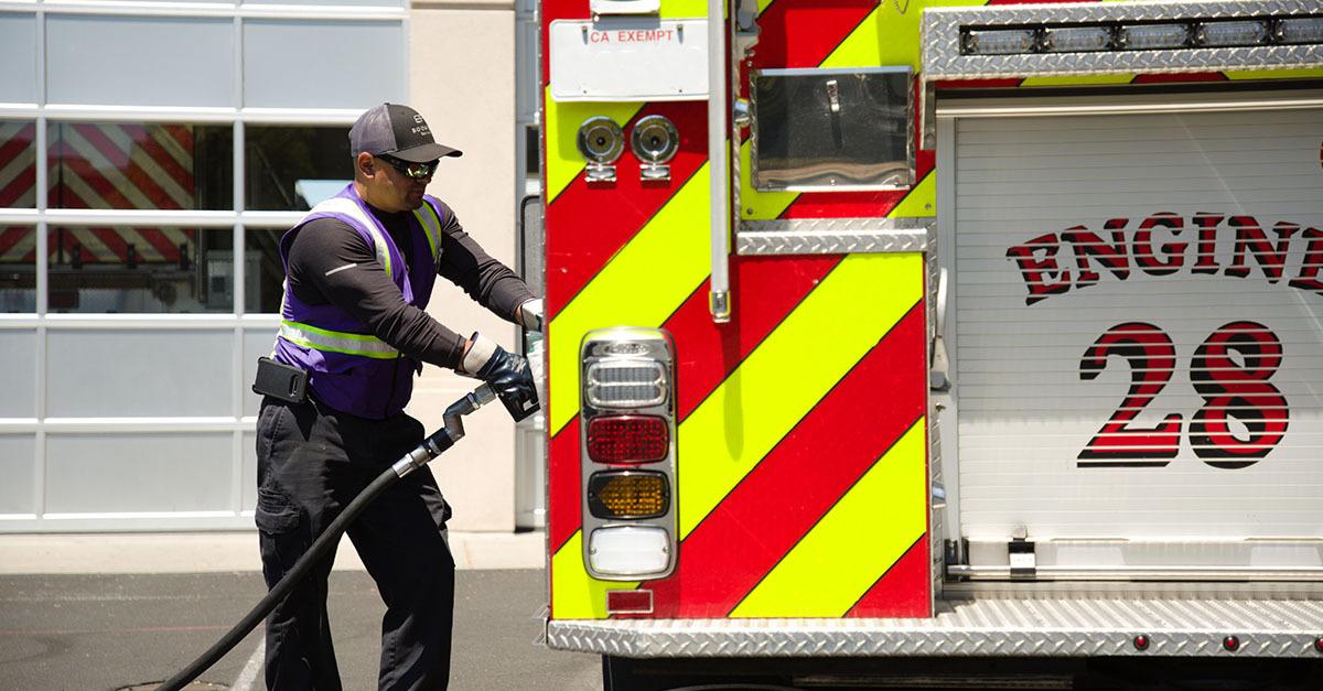 A Booster service professional fuels a fire engine with the number 28 on the back. 