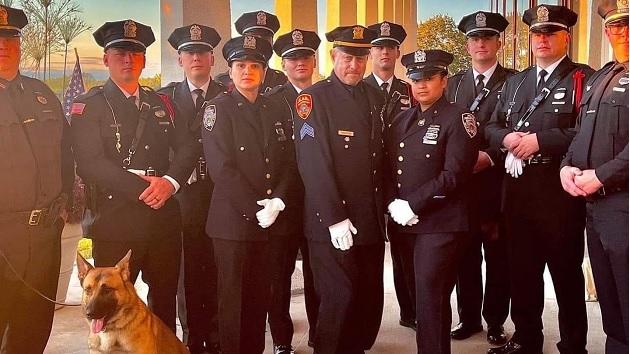 A group of police officers in dress uniforms standing in an outdoor structure.