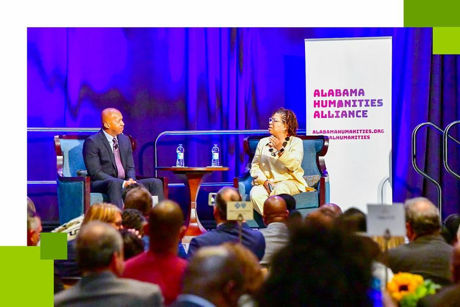 Bryan Stevenson and Michel Martin sit on stage in front of a crowd