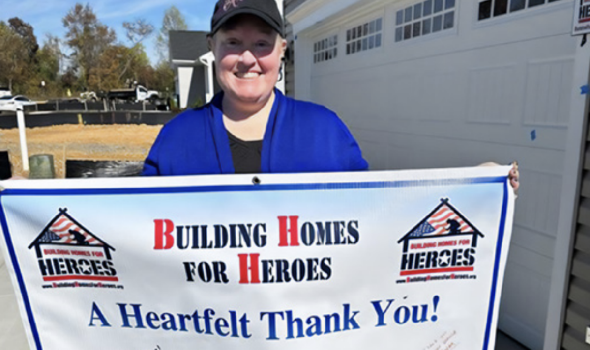 A person holding a Building Home for Heroes banner 