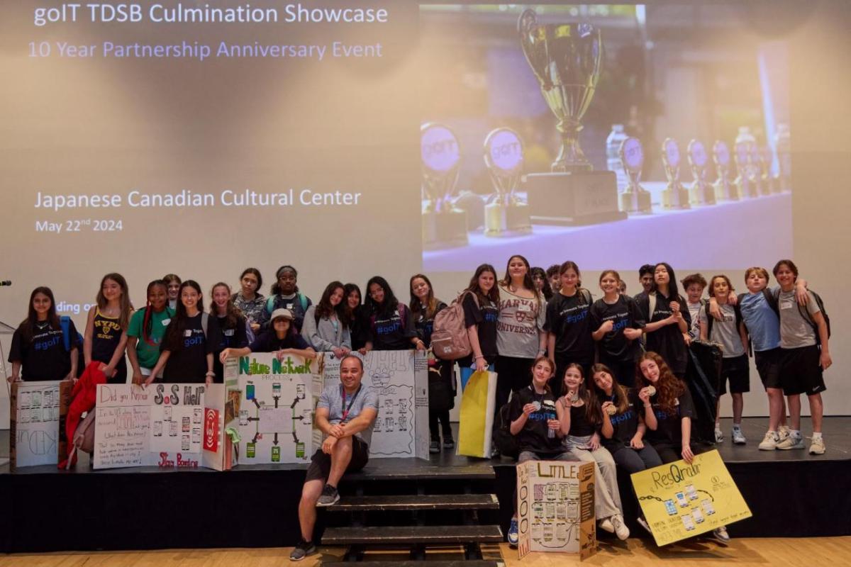 A group of students posed on a stage with project boards.