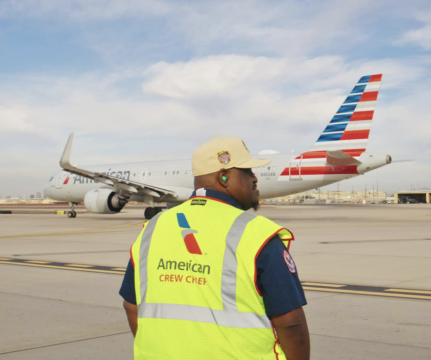 A person stood on an aeroplane runway wearing a hi-vis vest 