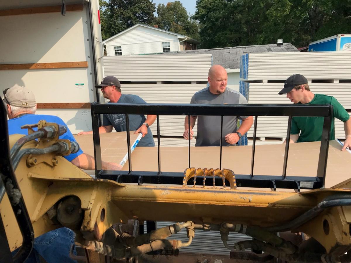 Men unloading wallboard from a truck