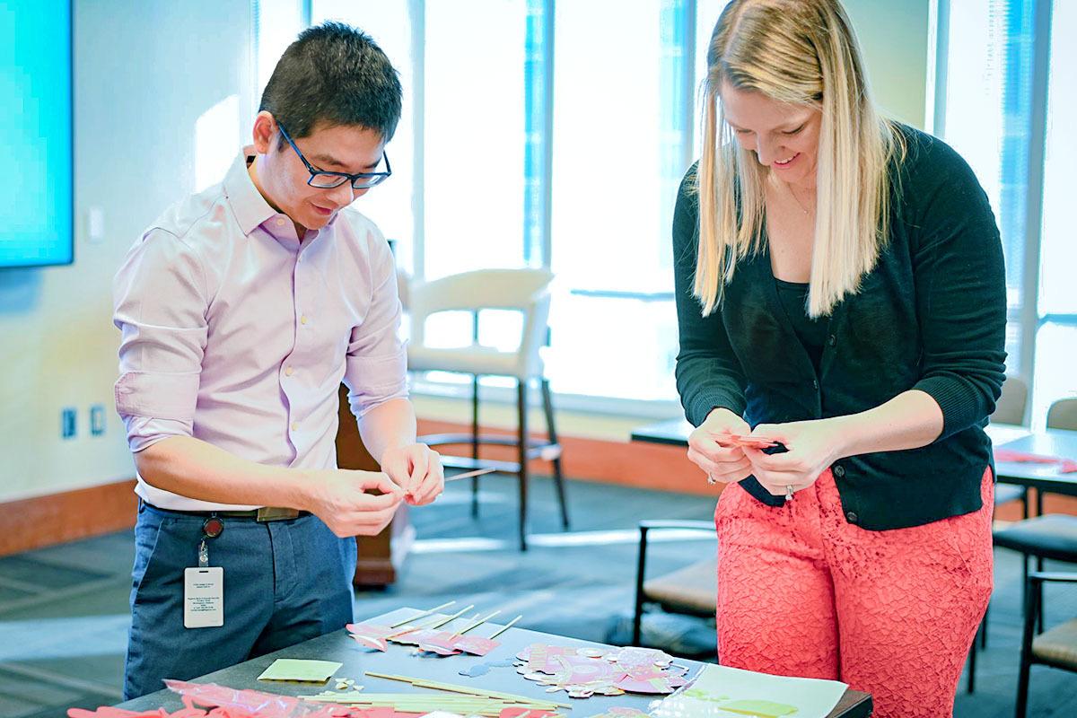 Two people stood at a table making decorations 