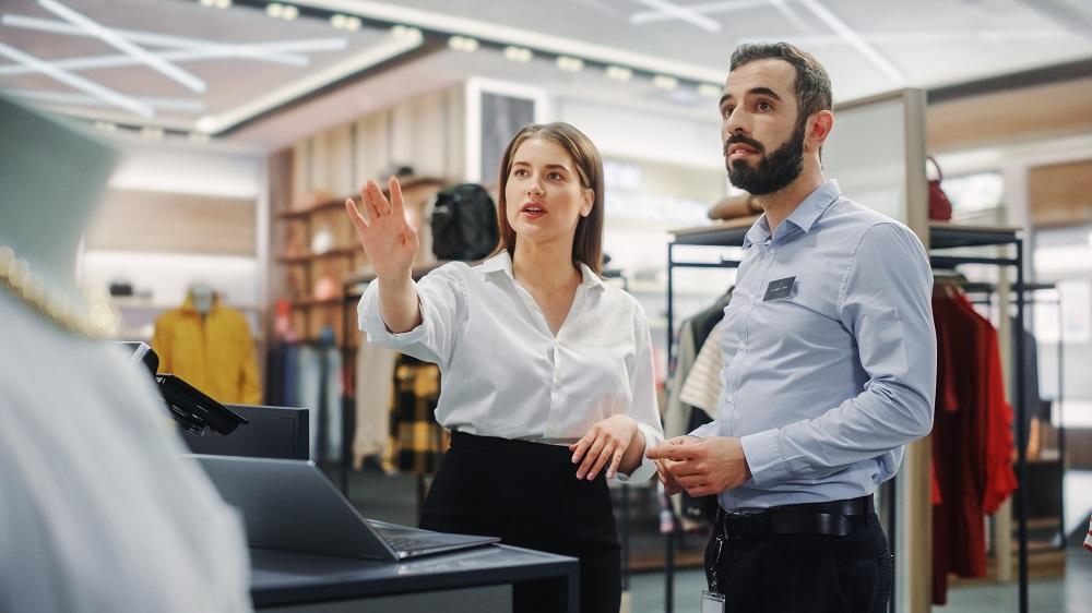 two retail workers looking at a display and talking