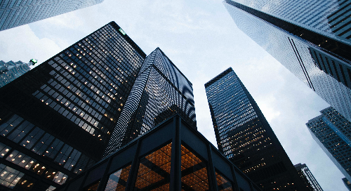 Photo looking up at the sky through a group of skyscrapers.