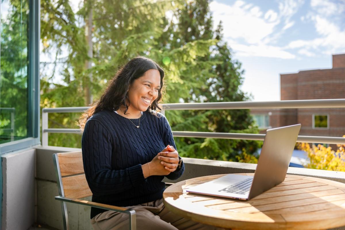 Female employee sitting outside in front of her laptop.