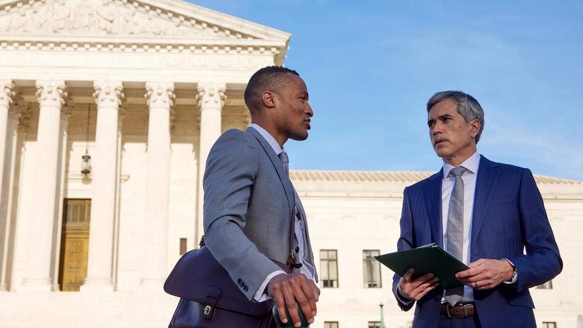 Two men in suits standing in front of a government building.