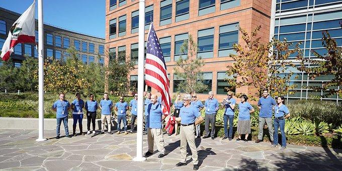 employees standing outside near American flag