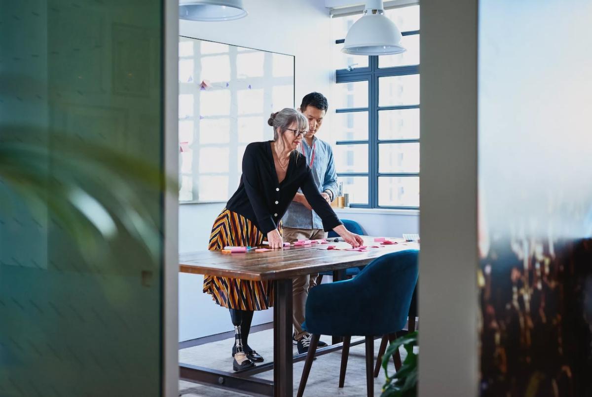 Two people at a table looking at a garment. The female has a prosthetic leg.