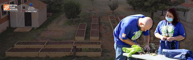 Two Home Depot volunteers, a man and a woman, are replanting vegetables in a vegetable box.