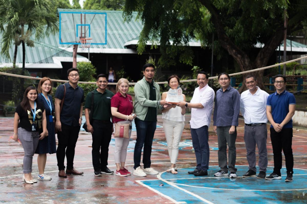 a group of people on a basketball court, three holding an award