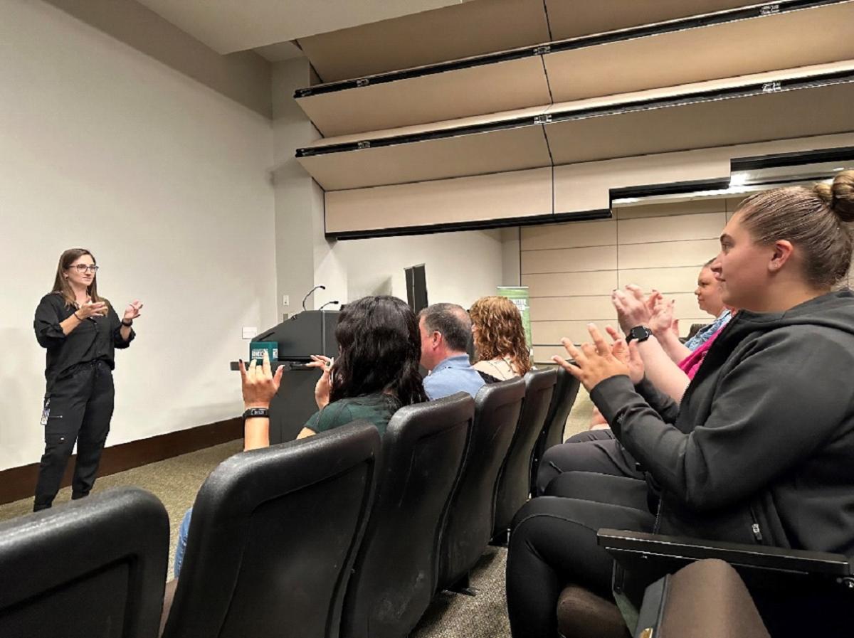 Moratz (left) teaching the sign for basketball during an ASL class at the DICK’S Sporting Goods Customer Support Center