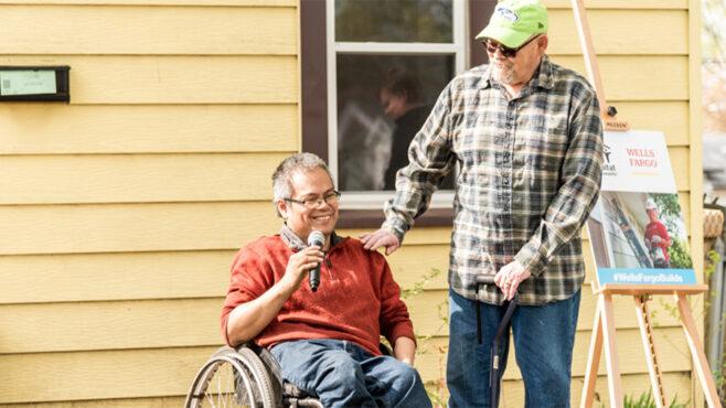 Man sitting in wheelchair in front of a house.