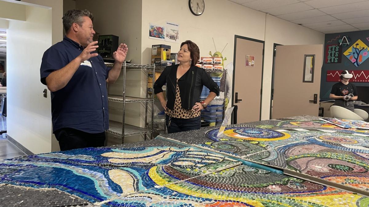 Man and woman talking in front of mosaic tiles