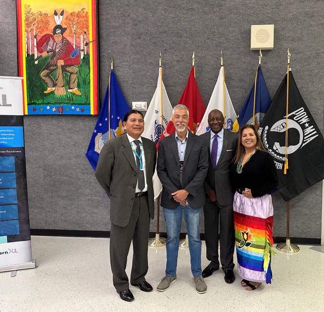 Four people posed in front of many flags.